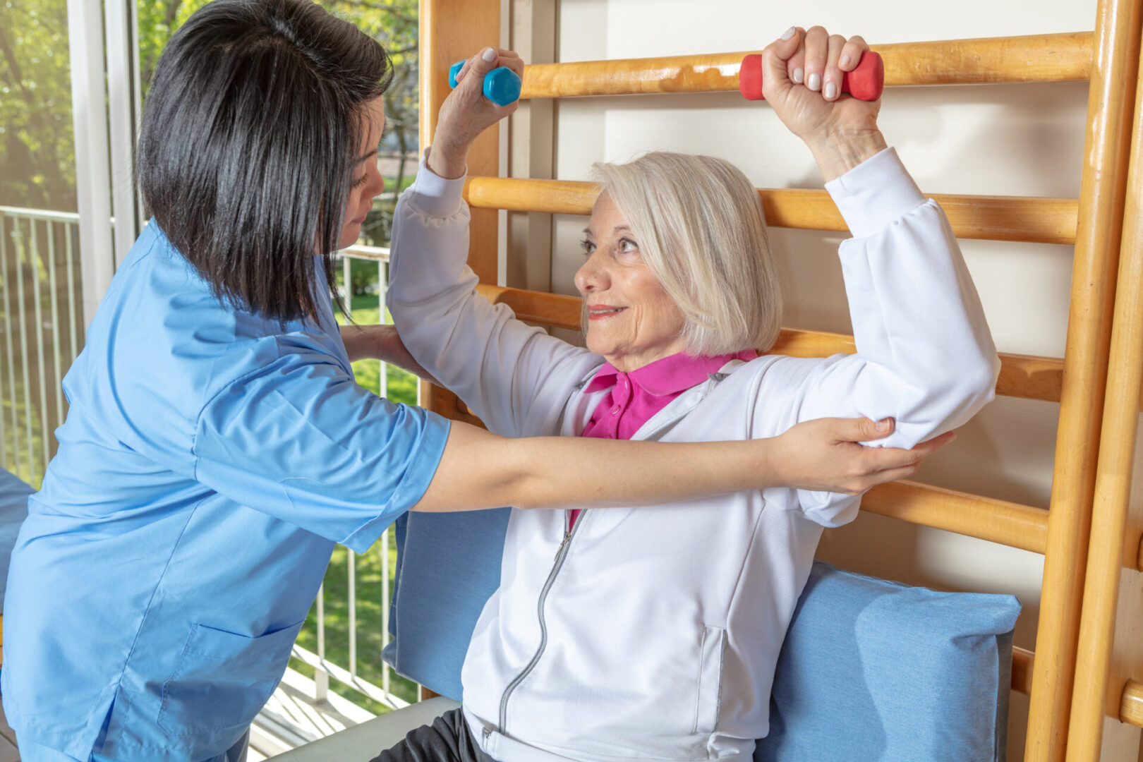 A woman is helping an older person exercise.