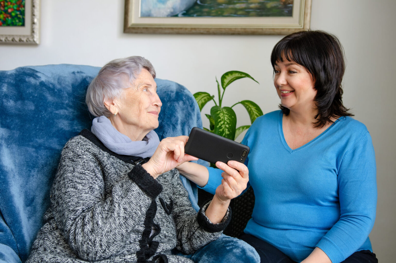 A woman showing an older lady something on her phone.